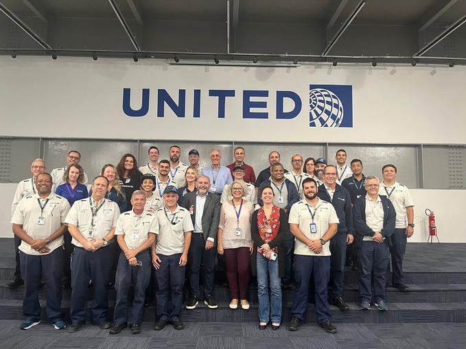 Equipe de uma companhia aérea reunida em frente ao logotipo da empresa